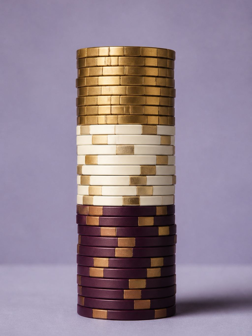 Column of plum, cream and brass casino chips in a studio still life