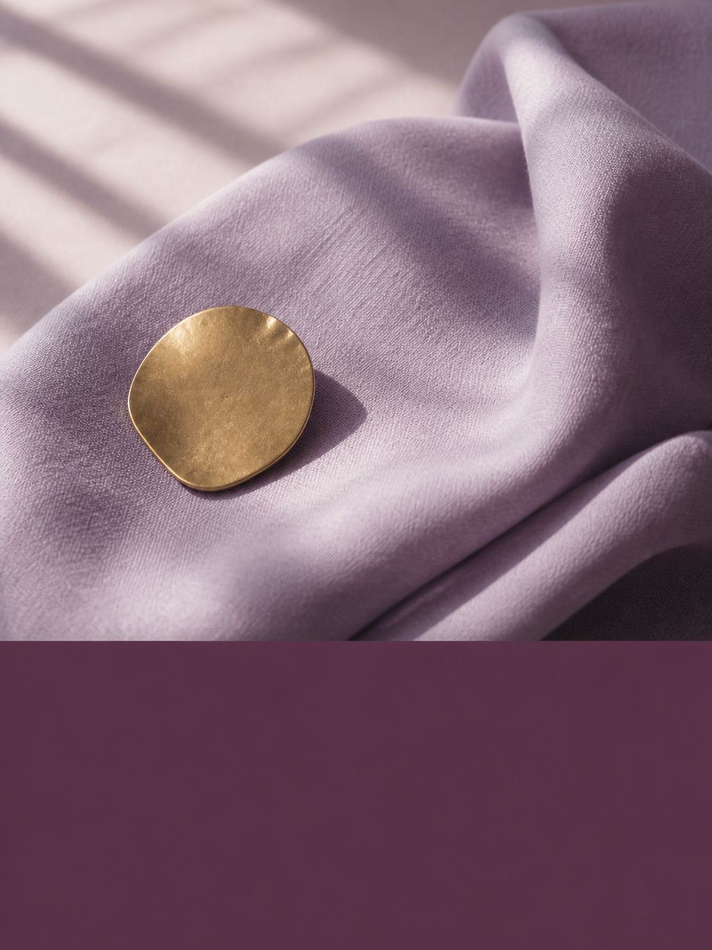 A single brass chip on folded cloth with a plum colour block