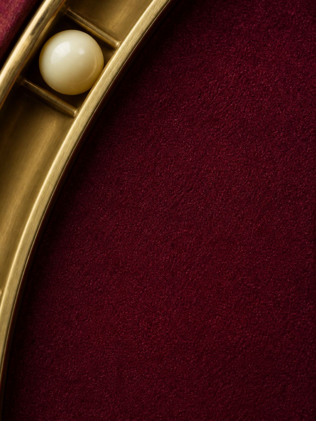 Roulette ball in a brass track, close-up on plum felt